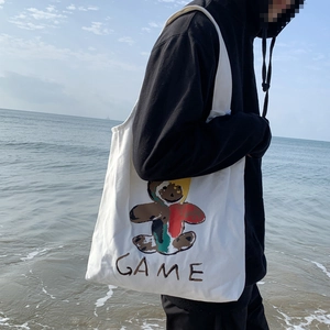 Détail d'un sac cabas en toile blanche avec imprimé ours graffiti sur fond de plage