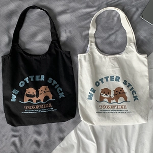 Detailansicht von schwarzen und weißen Canvas-Taschen mit süßem Otter-Cartoon-Aufdruck