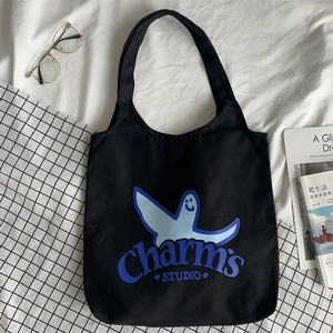 Detail of black canvas tote bag with blue cartoon print and Charm's STUDIO text design