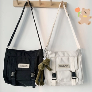 Detail of canvas messenger bags in black and beige with buckle straps and brand patch