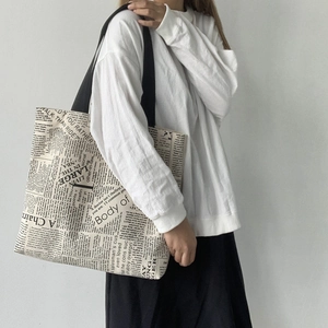 Detail of large canvas tote bag with retro newspaper print and black shoulder straps