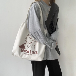 Detail of cream canvas tote bag with brown bear print and Good Luck lettering text