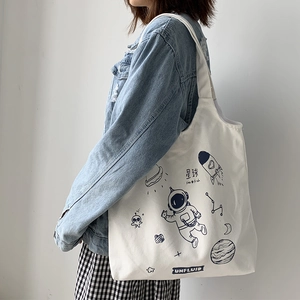 Detailed close-up of white canvas tote bag featuring blue space astronaut illustrations