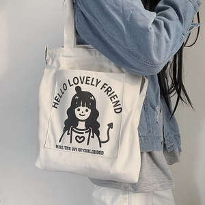 Detail of white canvas tote bag with black cartoon girl print and adjustable shoulder strap