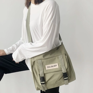 Detail of sage green nylon messenger bag with adjustable buckles and branded woven label