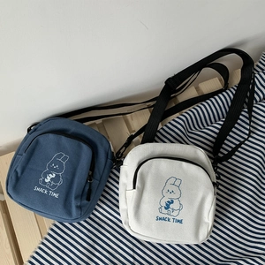 Detail of canvas crossbody bags in blue and white with cartoon rabbit and zip pockets