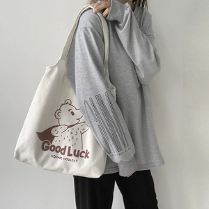 Detail of canvas tote bag featuring bear print and 'Good Luck' text in casual style