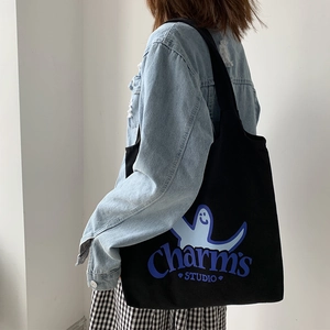 Detail view of black canvas tote bag with blue ghost print worn by model with denim jacket
