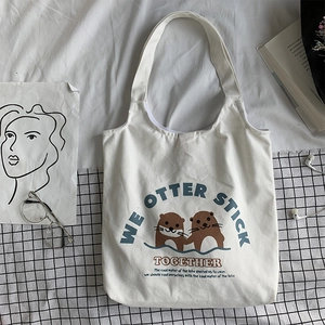 Nahaufnahme der weißen Segeltuchtasche mit Ottermotiv und we otter stick together Aufdruck