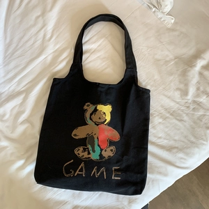 Détail du sac cabas en toile noire avec un ours coloré et une inscription GAME stylée