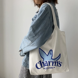 Detailed shot of white canvas tote bag with blue ghost print and wide shoulder strap