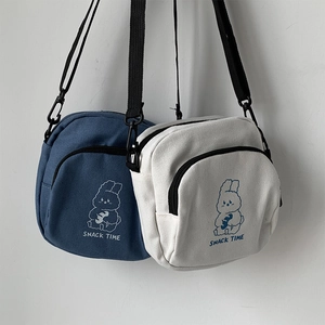 Detail of canvas crossbody bags in blue and beige featuring cute cartoon rabbit prints