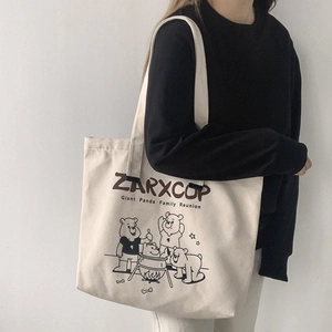 On-shoulder view of large canvas tote bag with cartoon bear print and ZARXCOP logo