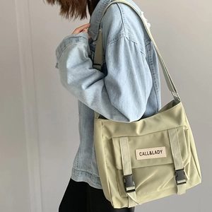 Detail of light green nylon messenger bag featuring adjustable straps and buckle closures
