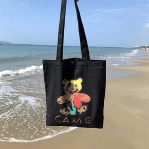Sac fourre-tout en toile noire avec motif ours coloré et longues anses sur la plage