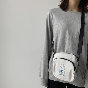 Close-up of cute rabbit print on a white canvas crossbody bag with black strap