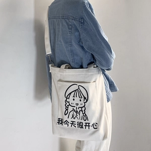 Close-up of a white canvas crossbody bag featuring a cute cartoon girl illustration