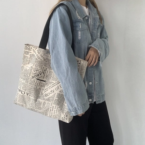 Detail view of large canvas tote bag with vintage newspaper print and black strap