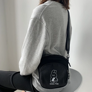 Detail of black canvas crossbody bag featuring a cute cartoon rabbit print and snack time text