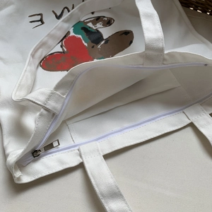 Détail du sac cabas en toile montrant la fermeture éclair et la poche intérieure