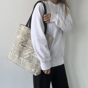Detail of vintage newspaper print canvas tote bag with large capacity and black straps