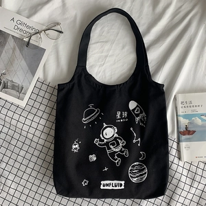 Detail of black canvas tote bag featuring white astronaut and space themed prints