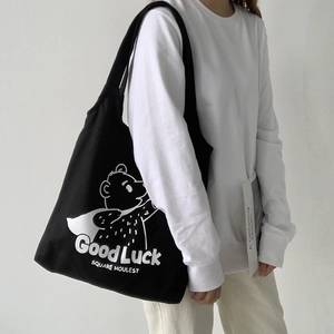Detail of black canvas tote bag featuring white cartoon bear print and Good Luck text