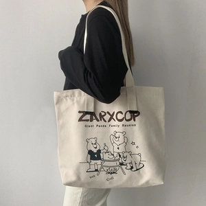 Detail of a large off-white canvas tote bag featuring a black and white cartoon bear print