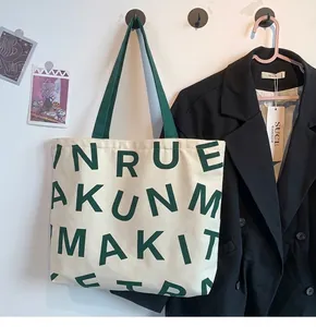 Detail of canvas tote bag with green letter print and sturdy webbing handles