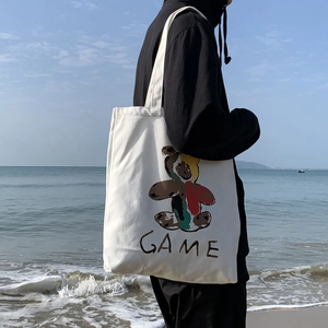 Détail d'un sac cabas en toile blanche avec motif d'ours coloré et inscription texte GAME