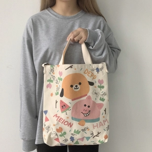 Détail du sac cabas en toile crème avec illustrations de dessins animés et poignées souples