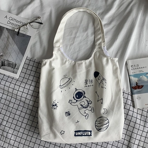 Detail of canvas tote bag showing space theme graphics with rocket and astronaut illustrations