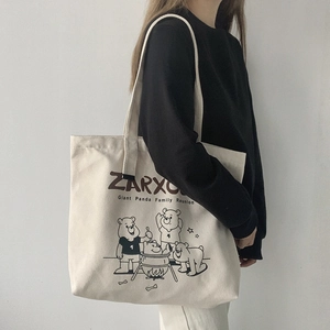 Detailed view of the large ivory canvas tote bag featuring a black panda cartoon illustration
