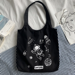 Detail of black canvas tote bag featuring white astronaut and galaxy space illustrations