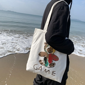 Détail du sac cabas en toile avec imprimé ours en peluche coloré et lettrage GAME à la plage