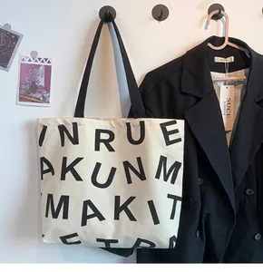 Detail of canvas tote bag with bold lettering and durable black handles for travel