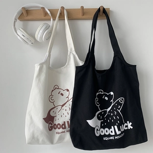 Detail of canvas tote bags with bear print and Good Luck text in black and cream