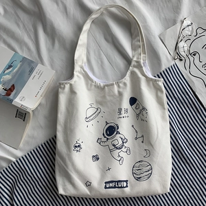 Detail view of canvas tote bag with space illustrations of astronauts and planets