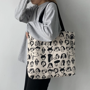 Artistic canvas tote bag with hand-drawn portraits worn by a model in a minimalist setting