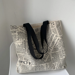 Detail of large canvas tote bag featuring vintage newspaper print and black woven handles