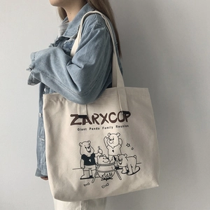 Detail of canvas tote bag with ZARXCOP bear print shown on a model wearing denim