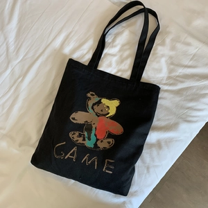 Détail à plat d'un sac cabas en toile noire avec un imprimé d'ours artistique coloré