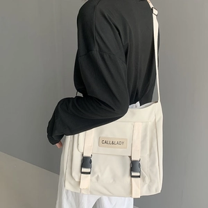 Detail of off-white nylon messenger bag with CALL&LADY label and black buckles