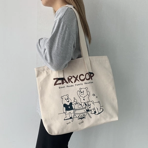 Side view of large cream canvas tote bag with black bear illustration and wide shoulder strap