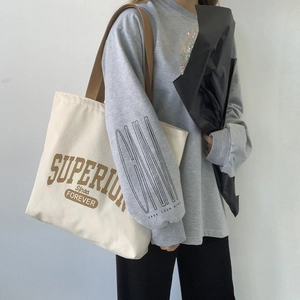 Detail of off-white canvas tote bag featuring brown retro Superior lettering and vintage style