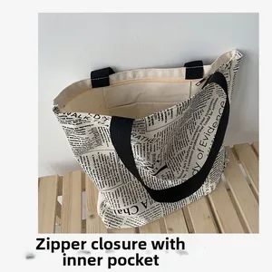 Detail view of large canvas tote bag showing zipper closure and newspaper print