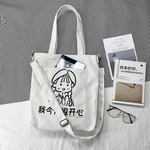 Minimalist canvas tote bag with cartoon print and adjustable strap shown with a tablet
