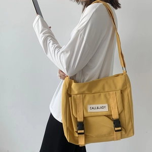 Close-up of yellow nylon messenger bag with Call & Lady label and adjustable strap