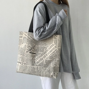 Detailed view of large canvas tote bag with vintage newspaper print and black straps