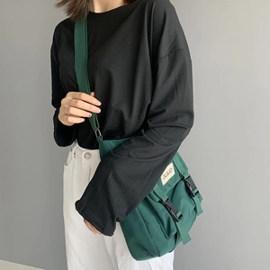 Detailed view of dark green canvas messenger bag with plastic buckle and fabric label